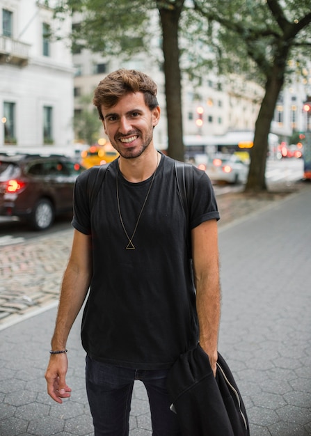 Free Photo young man in black smiling on sidewalk