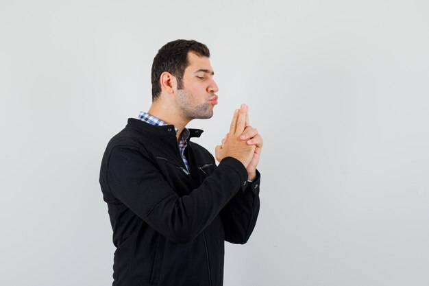 Young man blowing on finger pistol in shirt, jacket and looking confident