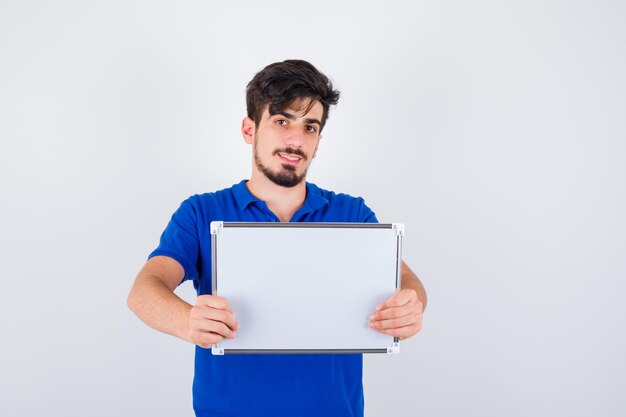 Young man in blue t-shirt holding whiteboard and looking happy