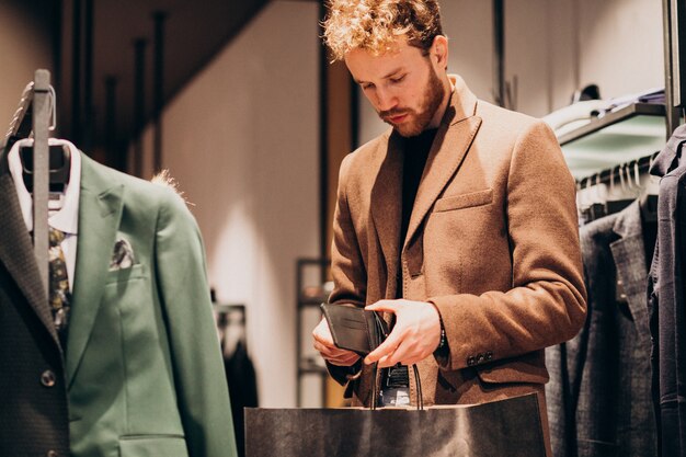 Young man buying cloths and paying with cash at a shop