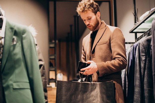 Young man buying cloths and paying with cash at a shop