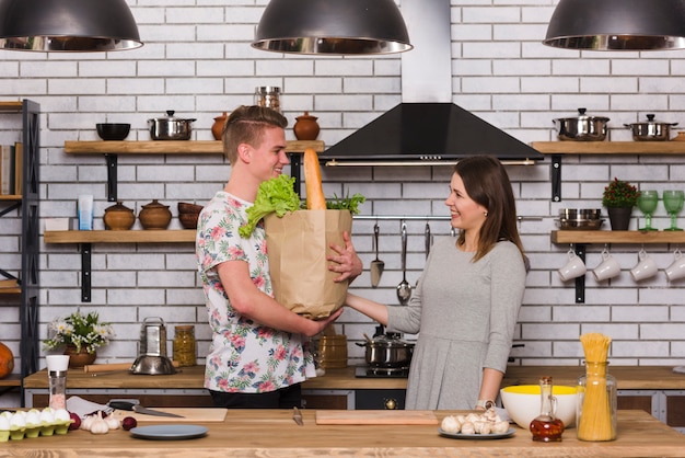 Free photo young man carrying groceries for girlfriend