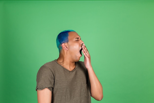 Free Photo young man in casual on green wall cover mouth with hand yawning