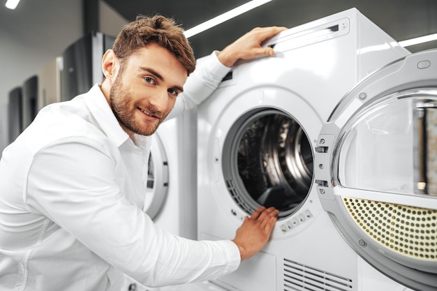 Free photo young man choosing new washing machine in household appliances store