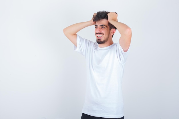 Young man clasping head in hands in t-shirt and looking cute