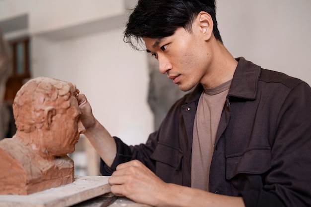 Free photo young man clay sculpting side view