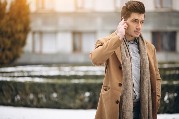 Free photo young man in coat talking on the phone outside