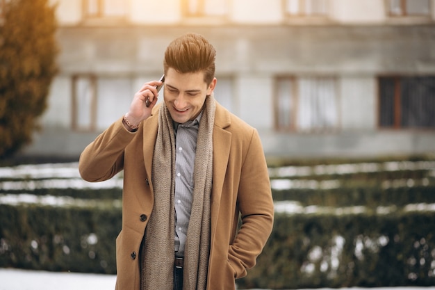 Young man in coat talking on the phone outside