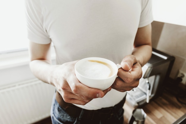 Young man cooking coffee at home with automatic coffeemachine.