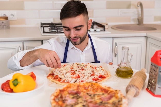 Free photo young man cooking pizza in kitchen