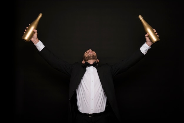 Free photo young man in dinner jacket with bottles of drink