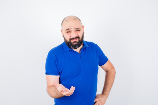 Free photo young man discussing something while showing hand gestures in blue shirt and looking focused. front view.