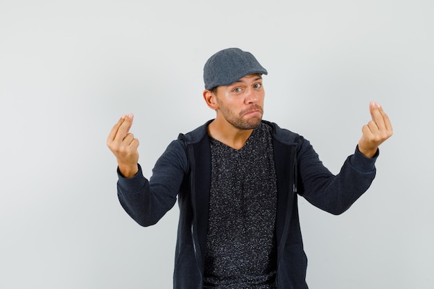 Young man doing italian gesture with hands and fingers in t-shirt, jacket, cap , front view.