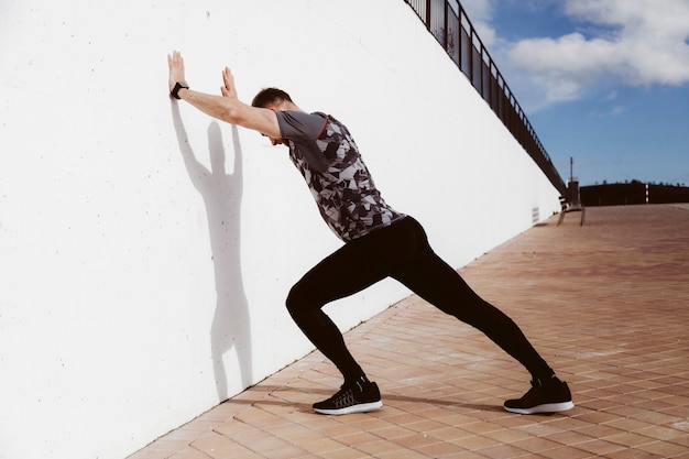 Free photo young man doing standing wall push up