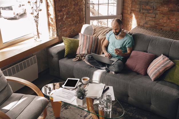 Free Photo young man doing yoga at home while being quarantine and freelance working