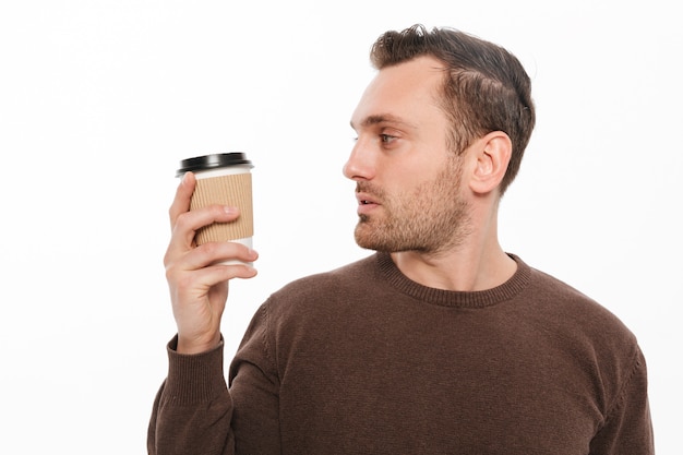 Young man drinking coffee. Looking aside.