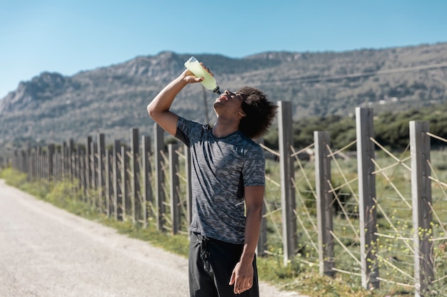 Free Photo young man drinking water on road