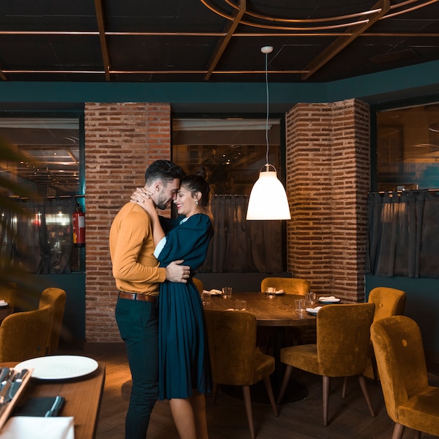 Young man embracing with happy woman in restaurant