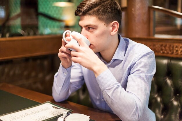 Young man enjoying hot beverage in restaurant