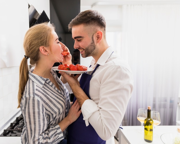 Free photo young man feeding woman with tomatoes