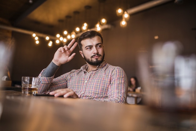 Young man gesturing while drinking alcohol at bar