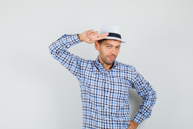 Young man gesturing with hand and fingers to head in checked shirt and looking confident.