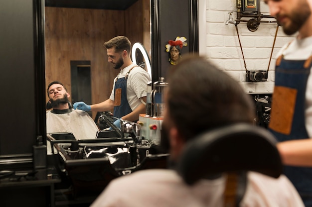 Free Photo young man getting his beard styled at the barber