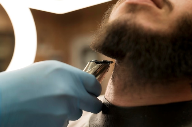 Young man getting his beard styled at the barber