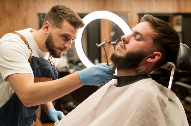 Young man getting his beard styled at the barber