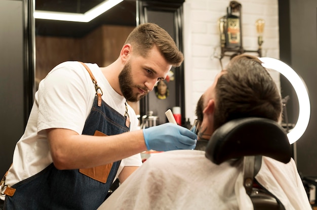 Free photo young man getting his beard styled at the barber