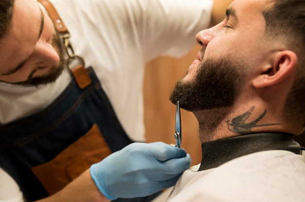 Young man getting his beard styled at the barber