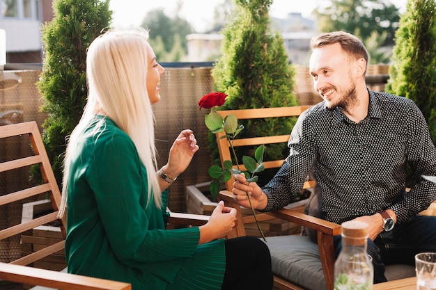 Young man giving beautiful rose to attractive lady