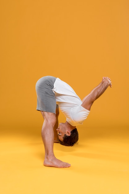 Young man in head to toes yoga pose