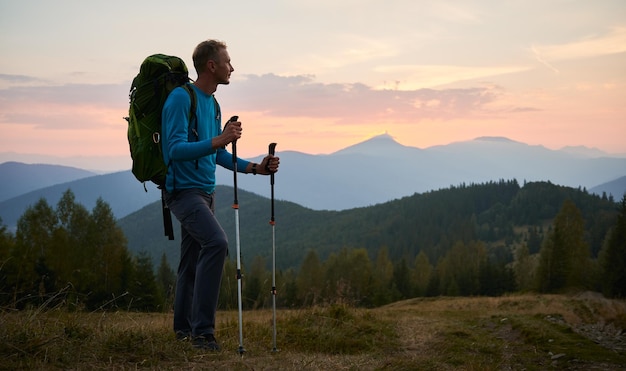 Free Photo young man hiking in the mountains at sunset