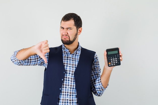 Free photo young man holding calculator, showing thumb down in shirt