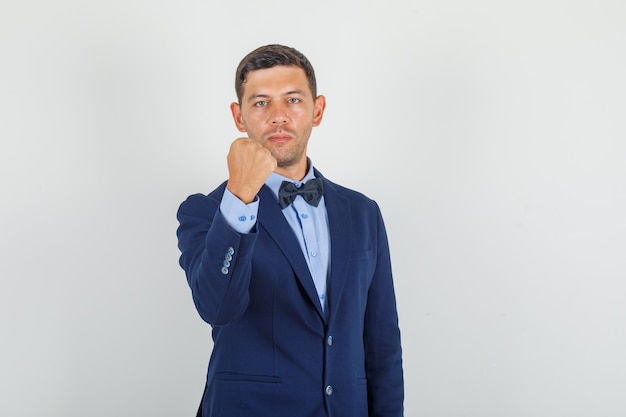 Young man holding clenched fist in suit and looking strong