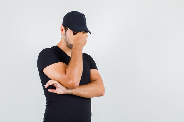 Young man holding hand on face in black t-shirt