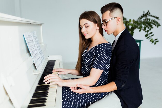 Young man holding hand of her girlfriend for playing piano