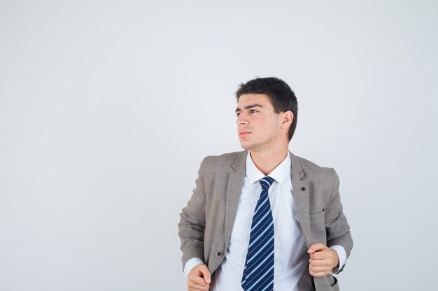 Young man holding hands on jacket in formal suit