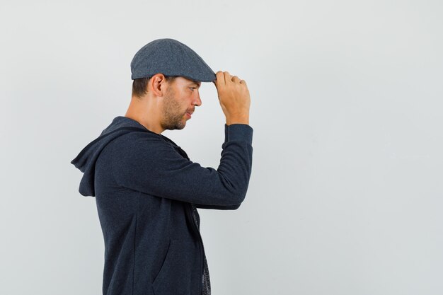 Free photo young man holding his cap in t-shirt, jacket and looking pensive .