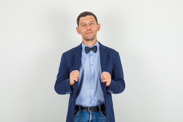 Free Photo young man holding his jacket in suit, jeans and looking serious