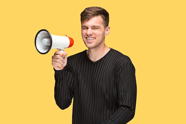 The young man holding a megaphone on on yellow background