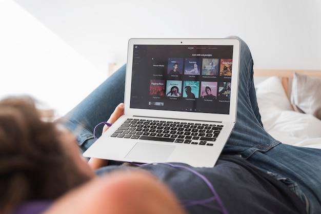 Young man holding modern device with spotify app