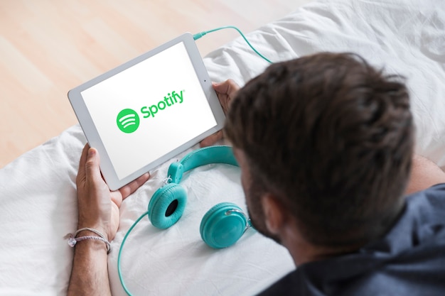 Young man holding modern device with spotify app