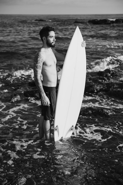 Free photo young man holding surf board in water