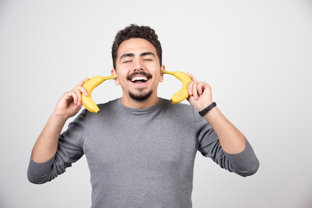 A young man holding two fresh bananas .