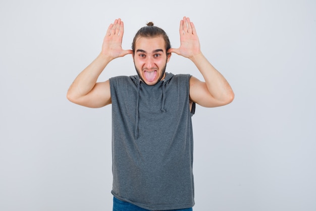 Young man in hoodie making grimace and looking funny , front view.