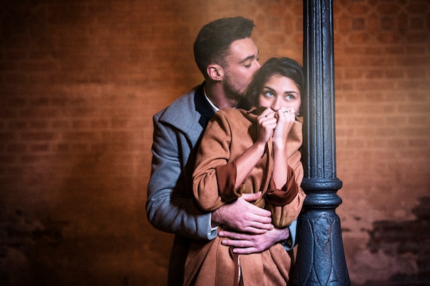 Young man hugging woman near street lamp