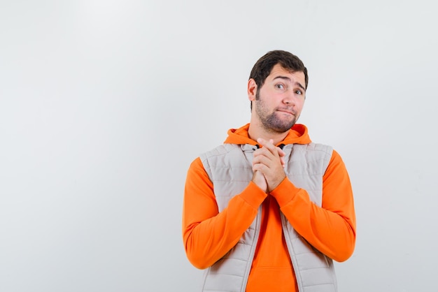 Free photo the young man is begging by clasping his hands on white background