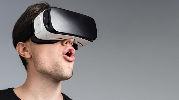 A young man is excited while wearing VR glasses gray background